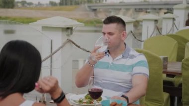 Açık terasta bir restoranda öğle yemeği alan genç erkek ve kadın.