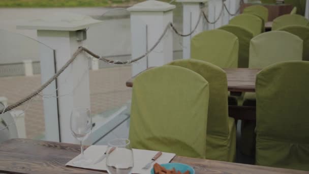 Un joven se sienta en una mesa en un restaurante con terraza .. — Vídeos de Stock