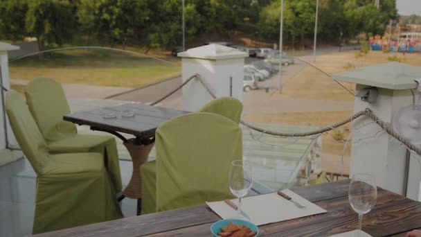 Красива жінка сідає за стіл у ресторані на відкритій терасі і кладе телефон на стіл . — стокове відео