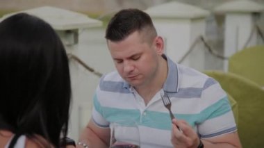 Açık terasta bir restoranda öğle yemeği alan genç erkek ve kadın.