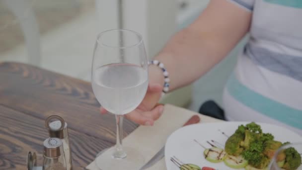 Joven bebiendo vino blanco en la terraza de un restaurante . — Vídeos de Stock