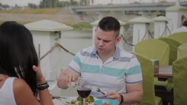 Молодой человек и женщина обедают в ресторане на открытой террасе . — стоковое видео