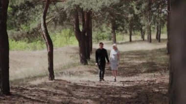 Güneşli ormanda el ele yürüyen aşık mutlu genç çift