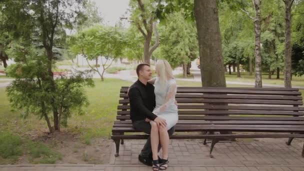 Счастливая влюбленная пара сидит на скамейке в городском парке . — стоковое видео