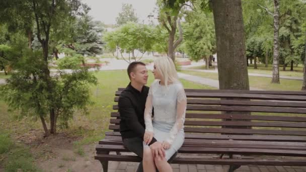 Bir şehir parkında bir bankta oturan aşk mutlu çift. — Stok video
