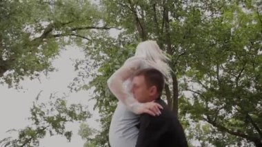 Adam kız arkadaşını parkta kollarına dönüyor. İyi ruh hali ve kahkaha.