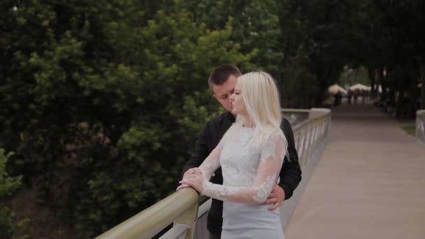 市内の公園の鉄橋の上に立って、抱きしめる愛の幸せなカップル. — ストック動画