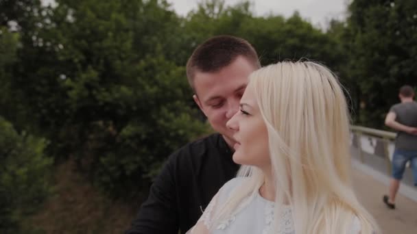Verliebtes glückliches Paar steht auf der Eisernen Brücke im Stadtpark und umarmt sich. — Stockvideo