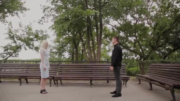 The guy is spinning his girlfriend in his arms in the park. Good mood and laughter. — Stock Video