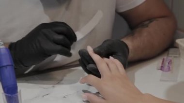 Profesyonel manikürcü adam parlatır ve bir tırnak dosyası ile kız çivi pürüzsüz.