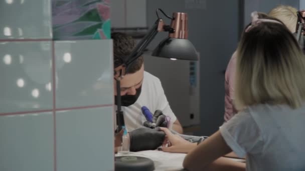 Professional manicurist man removes old nail polish from a girl using a special nail polish remover. — Stock Video