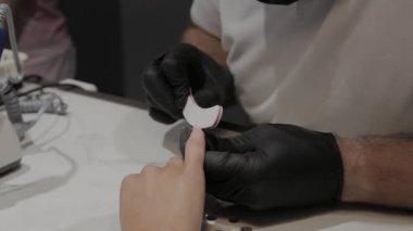 Profesyonel manikürcü adam parlatır ve bir tırnak dosyası ile kız çivi pürüzsüz.