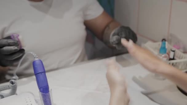 Professionele manicure man verwijdert oude nagellak van een meisje met behulp van een speciale nagellakremover. — Stockvideo