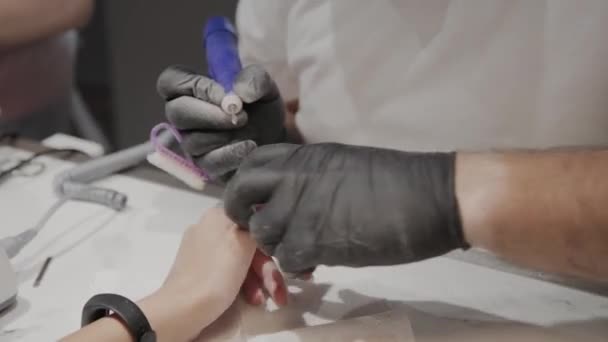 Hombre manicurista profesional elimina el esmalte de uñas viejo de una chica usando un removedor de esmalte de uñas especial . — Vídeos de Stock