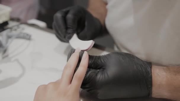 Профессиональный маникюр мужчина полирует и сглаживает ногти девочек с помощью ногтевой доски . — стоковое видео