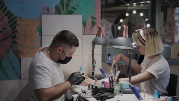 Professional manicurist man polishes and smoothes girls nails with a nail file. — Stock Video