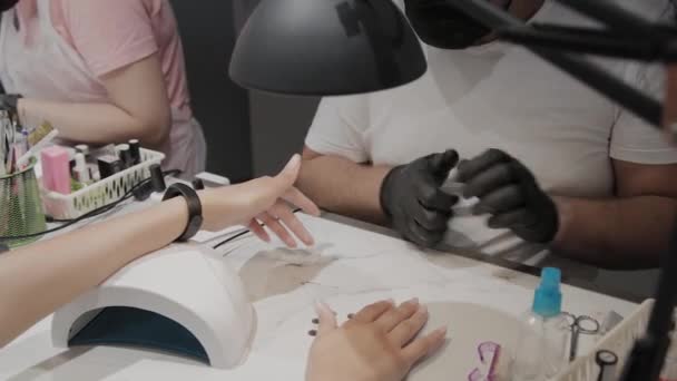 professionelle Maniküre Mann lackiert ein Mädchen Nägel.