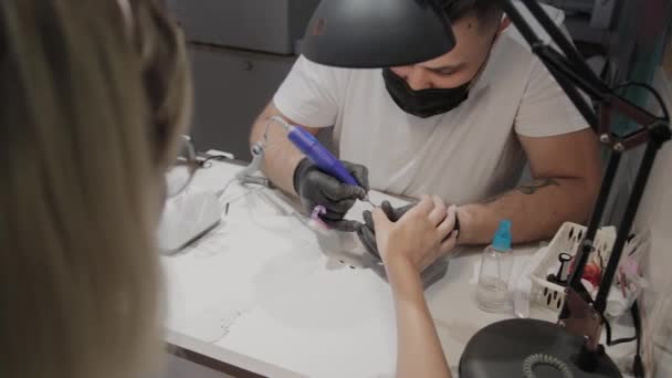 Professionele manicure man verwijdert oude nagellak van een meisje met behulp van een speciale nagellakremover. — Stockvideo