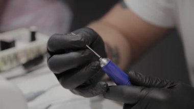 Profesyonel manikürcü adam özel bir oje çıkarıcı içine bir ipucu ekler.