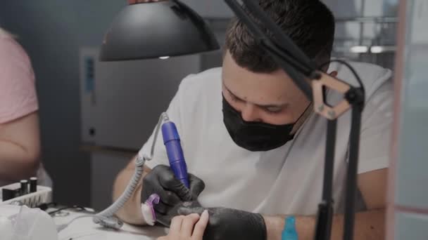 Professional manicurist man removes old nail polish from a girl using a special nail polish remover. — Stock Video