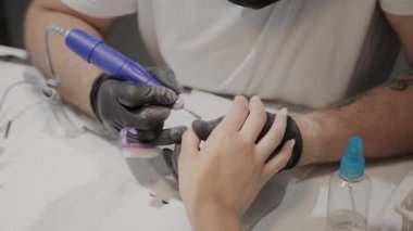 Profesyonel manikürcü adam özel bir oje çıkarıcı kullanarak bir kız eski oje kaldırır.