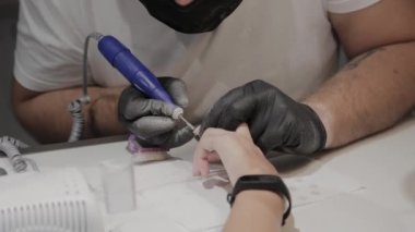 Profesyonel manikürcü adam özel bir oje çıkarıcı kullanarak bir kız eski oje kaldırır.