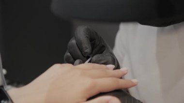 Profesyonel manikürcü adam vernishes bir kız çivi.