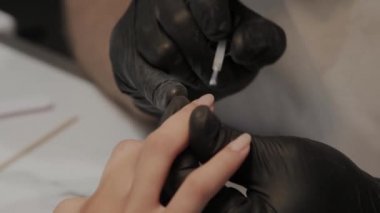 Profesyonel manikürcü adam vernishes bir kız çivi.