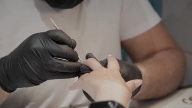 Profesyonel manikürcü adam vernishes bir kız çivi.