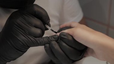 Profesyonel manikürcü adam vernishes bir kız çivi.