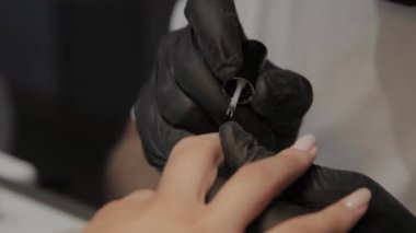 Profesyonel manikürcü adam vernishes bir kız çivi.