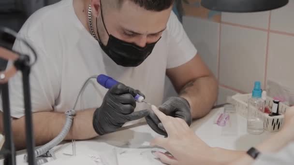 Professionele manicure man verwijdert oude nagellak van een meisje met behulp van een speciale nagellakremover. — Stockvideo