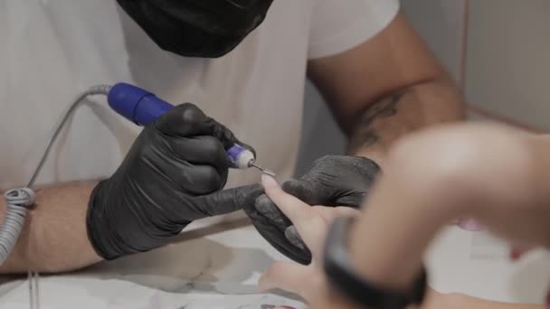 Professional manicurist man removes old nail polish from a girl using a special nail polish remover. — Stock Video