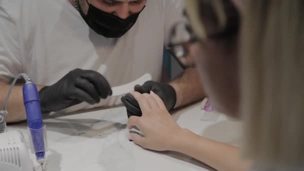 Profesionální manikúřník leštiče a uhlazuje dívky nehty se souborem nehtů. — Stock video