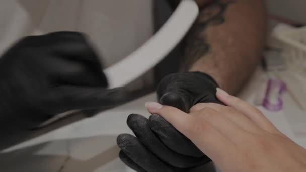 プロのマニキュアの男は、爪ファイルで女の子の爪を磨き、滑らかにします. — ストック動画