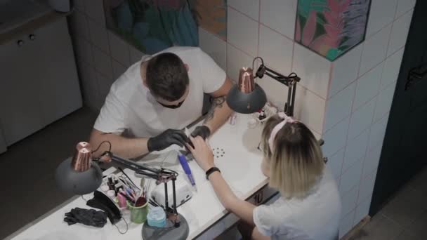 Professionele manicure man poliert en verzacht meisjes nagels met een nagel bestand. — Stockvideo