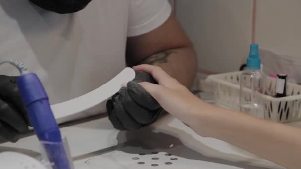Профессиональный маникюр мужчина полирует и сглаживает ногти девочек с помощью ногтевой доски . — стоковое видео