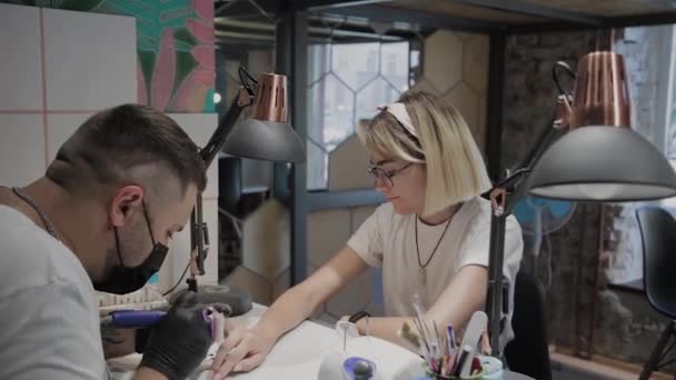 Professional manicurist man removes old nail polish from a girl using a special nail polish remover. — Stock Video