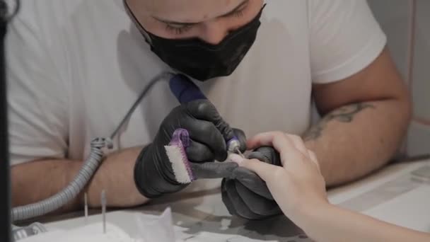 Hombre manicurista profesional elimina el esmalte de uñas viejo de una chica usando un removedor de esmalte de uñas especial . — Vídeo de stock