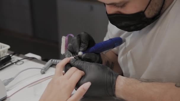 Hombre manicurista profesional elimina el esmalte de uñas viejo de una chica usando un removedor de esmalte de uñas especial . — Vídeos de Stock