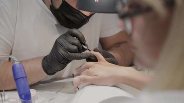 Homem manicure profissional enverniza umas unhas de meninas . — Vídeo de Stock