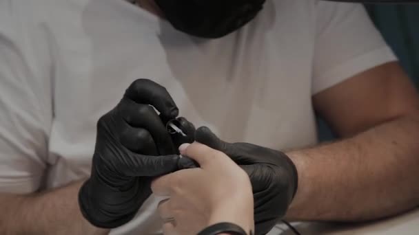 Homem manicure profissional enverniza umas unhas de meninas . — Vídeo de Stock