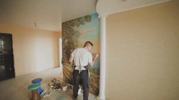 Profesionální umělec namaluje obrázek na stěně v bytě. — Stock video
