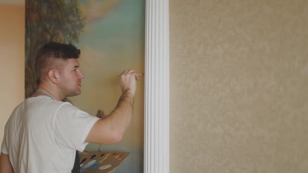 Профессиональный художник рисует картину на стене в квартире . — стоковое видео