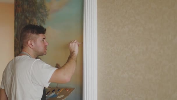 Professional artist paints a picture on the wall in the apartment. — Stock Video