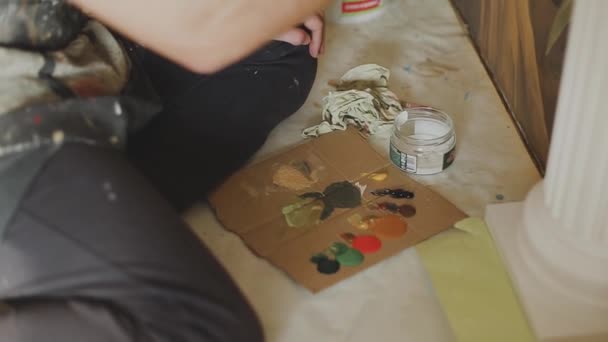 Художник змішує фарби на палітрі перед тим, як малювати картину, художник в студії, творець створює твір мистецтва . — стокове відео