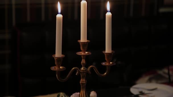 Beautiful burning candles in the twilight on the table. — Stock Video