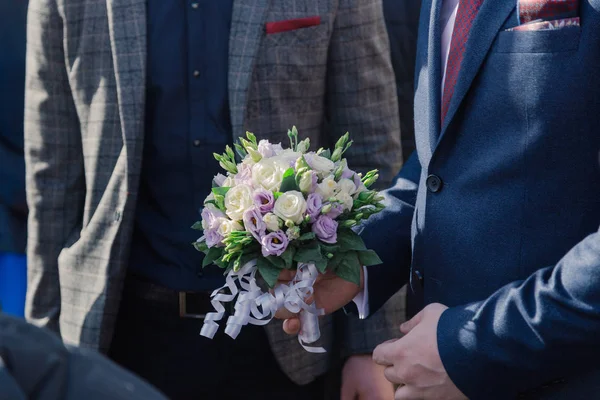 Elegante sposo tiene bouquet da sposa bianco. Giovane sposo in un vestito . — Foto Stock