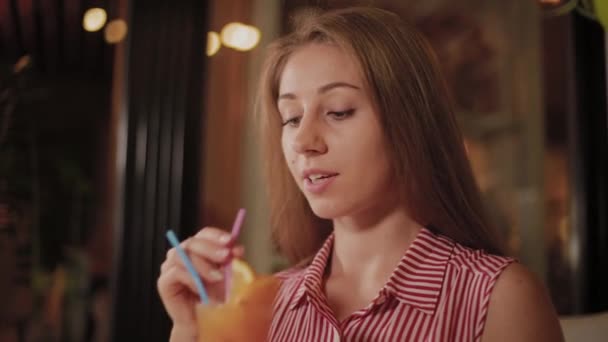 Belle fille avec un beau cocktail du soir lumineux et frais dans un café . — Video