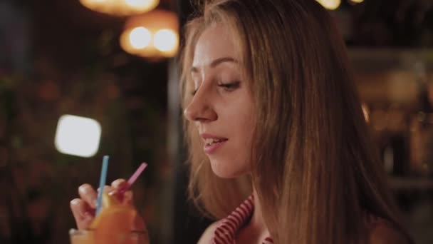 Beautiful girl with a beautiful fresh bright bright evening cocktail in a cafe. — Stock Video